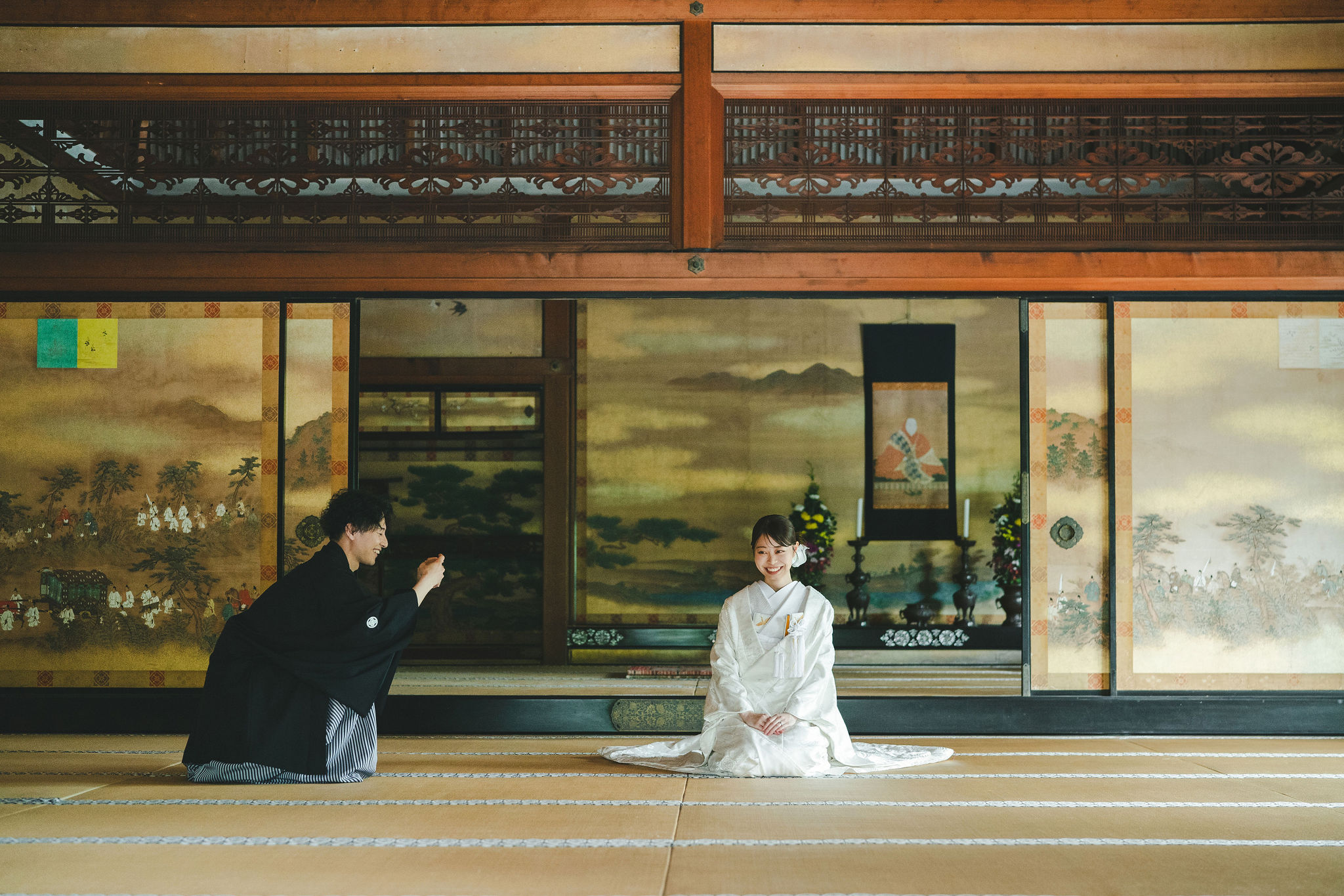 オフショット。仁和寺の宸殿にて、白無垢姿の新婦様を撮影する新郎様。