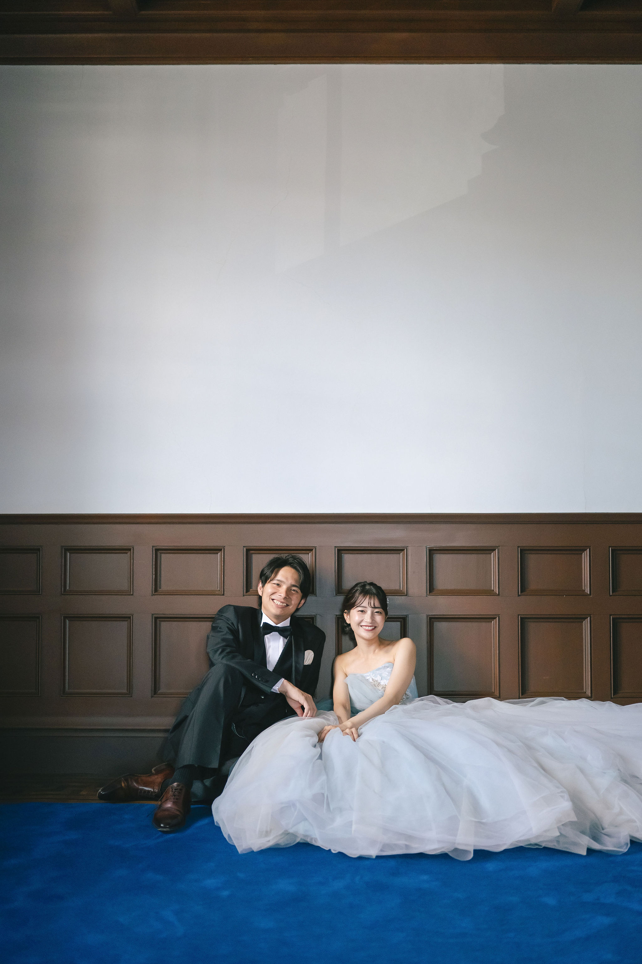 本願寺伝道院の室内で座りながら笑顔を見せる新郎新婦