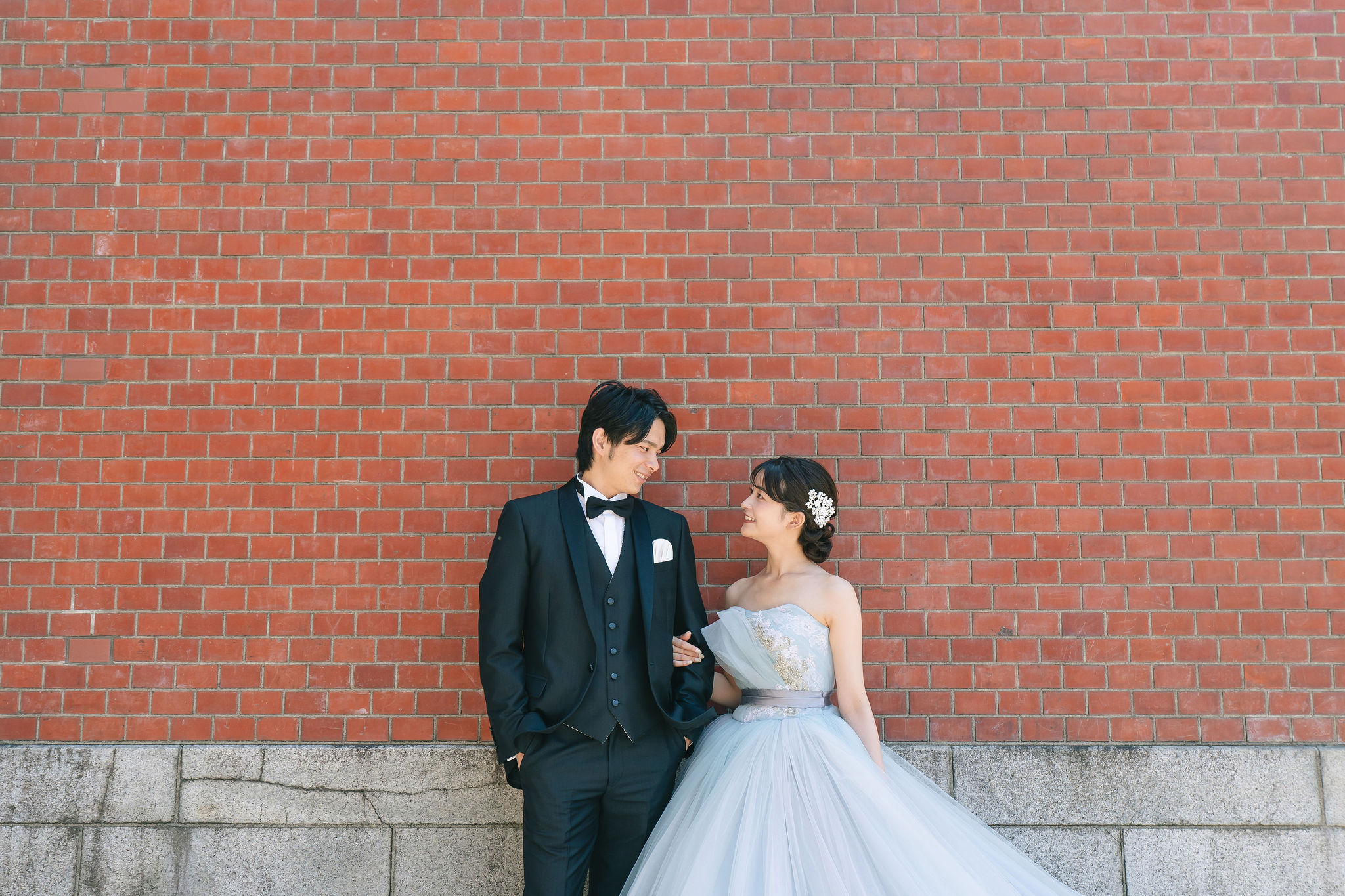 本願寺伝道院の赤レンガ壁を背景に立つ新郎新婦