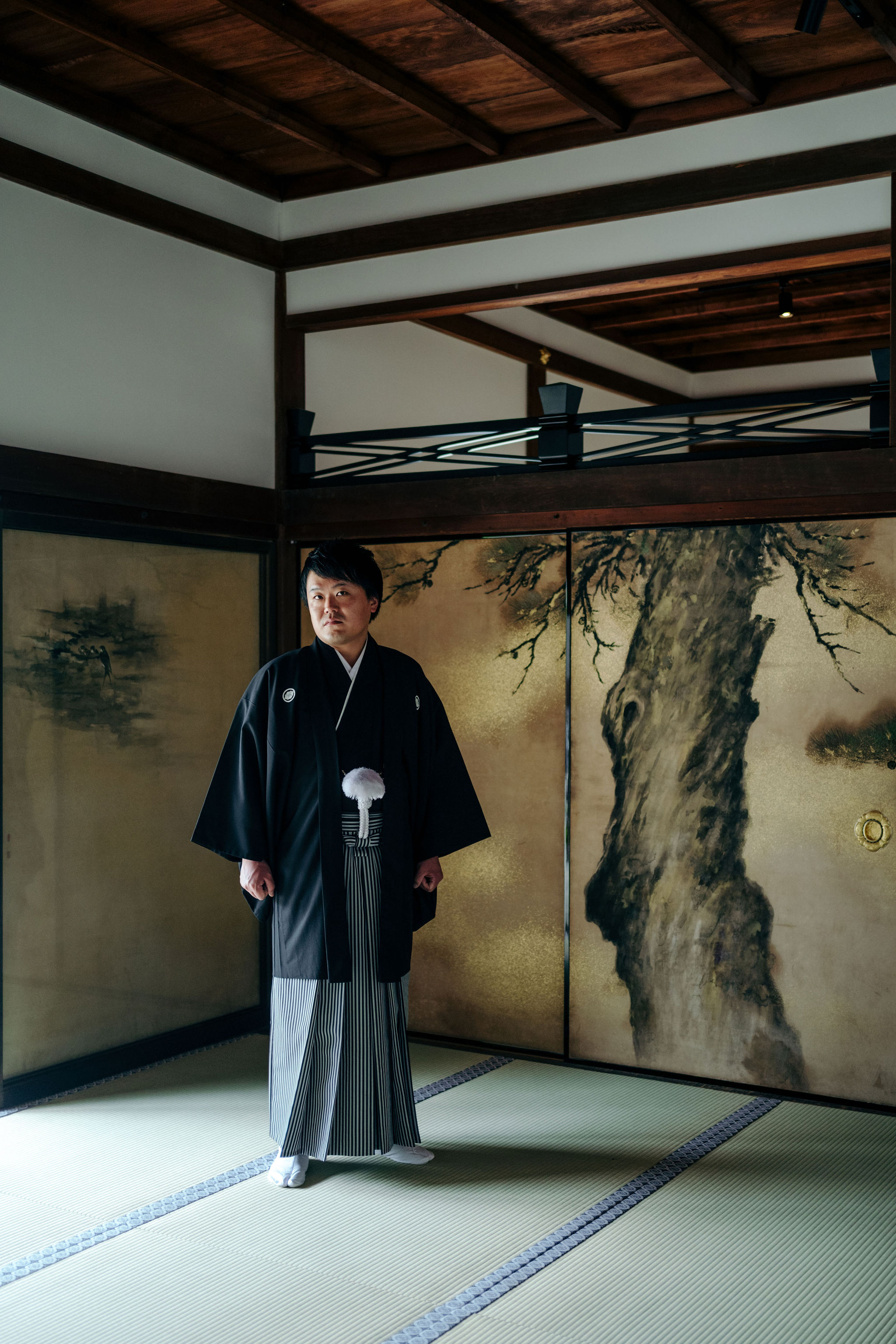 仁和寺白書院の襖絵を背景に立つ紋付袴姿の新郎